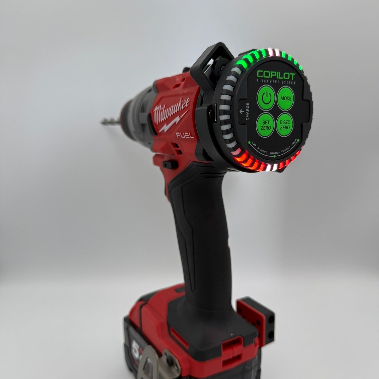 A Milwaukee cordless drill with a red and black body, featuring a circular LED alignment monitor on the back of the drill with green and white markings, shown against a neutral gray background.